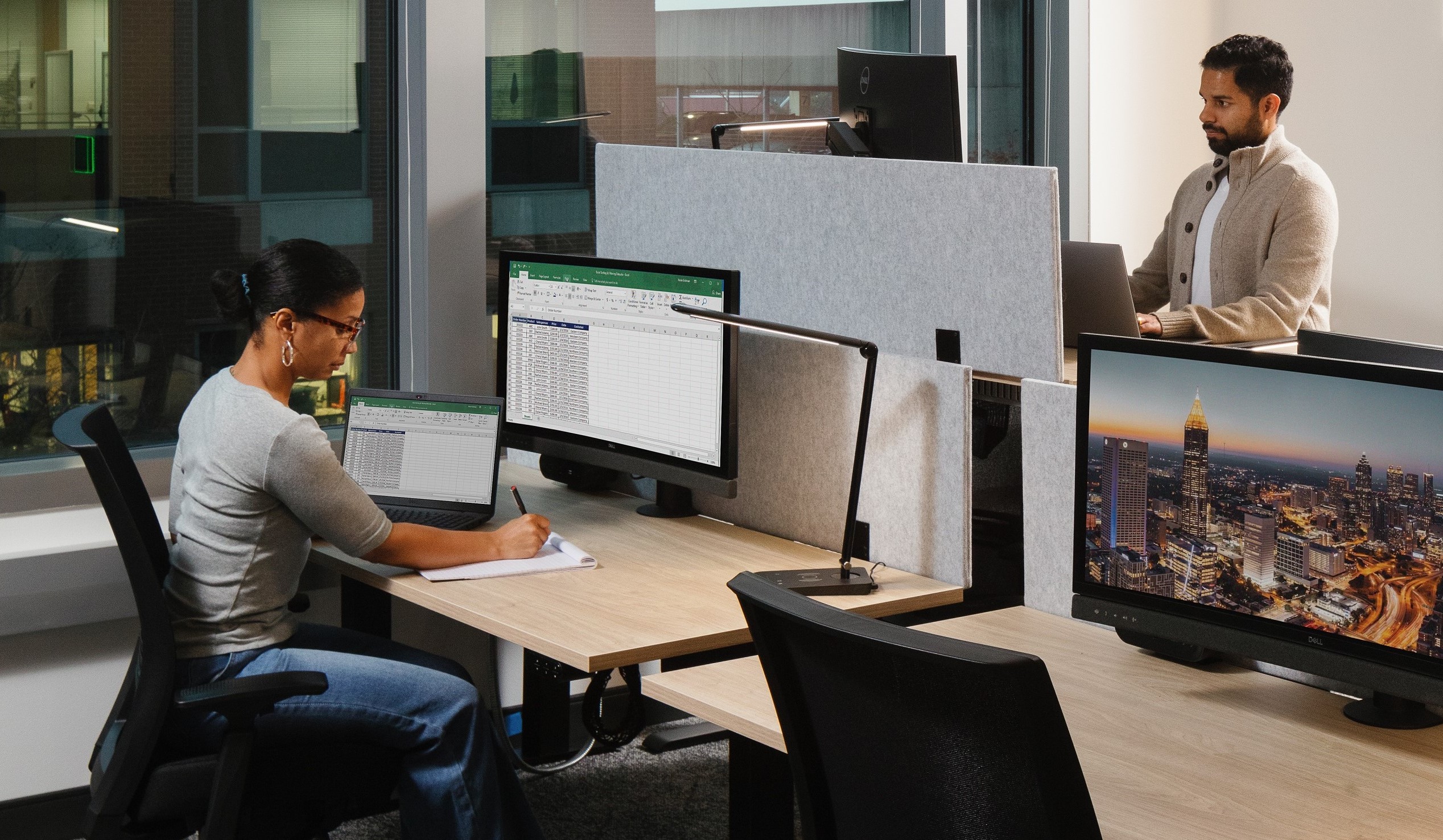 image of two employees working at a desk and a standing desk